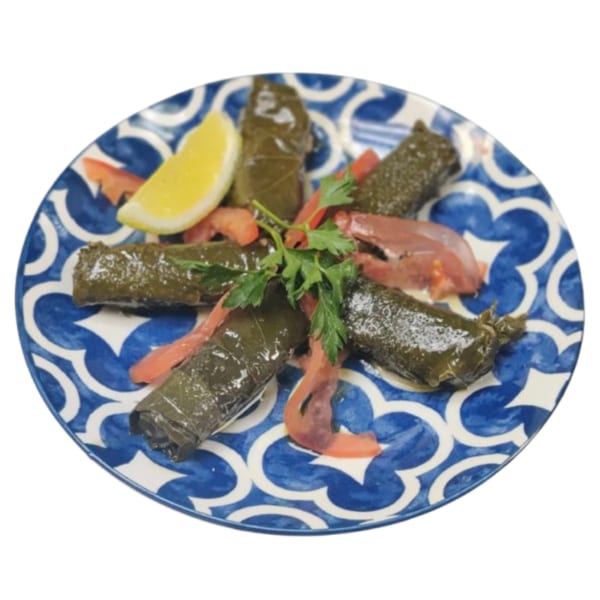 Persian dolmades, grape leaves stuffed with rice and herbs, garnished with lemon and tomato on a blue and white plate.
