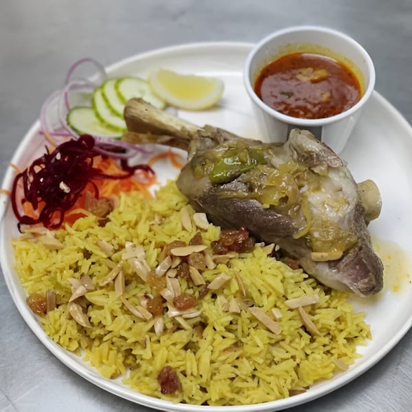 Persian lamb shank with yellow rice, almonds, raisins, and a side of red sauce and salad.
